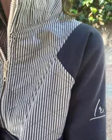 Buzo de algodón combinado en azul marino, con cuello alto, medio cierre frontal y un panel superior capitoneado con diseño a rayas.