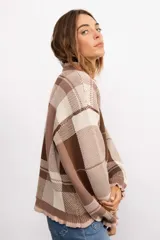 Sweater de punto con diseño de cuadros escoceses en tonos marrones y beige. Presenta un corte oversize, cuello redondo y terminaciones con volados en el cuello y los puños.