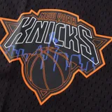 Short de básquet negro de tejido de malla, con cintura elástica y cordón ajustable de color naranja. Cuenta con el logotipo de los New York Knicks estampado en la pierna izquierda y la inscripción "KNI" en la pierna derecha.