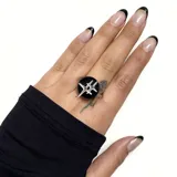 Anillo plateado con base circular negra y diseño geométrico plateado en el centro.