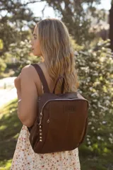 Mochila de cuero color marrón con cierre superior y bolsillos laterales fruncidos.