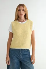Chaleco de tejido de punto en color amarillo, con cuello redondo y diseño sin mangas. Presenta un acabado texturizado y bordes con detalle en tono contrastante.