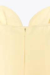 Vestido corto color amarillo pálido, con escote corazón, tirantes finos ajustables con detalle de lazos y falda acampanada.