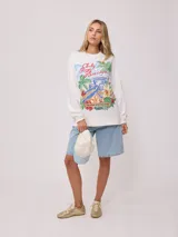 Gorra de lona color crema con visera celeste. Presenta bordado frontal en hilo azul claro con el texto "Rusty Tribe" y un pequeño diseño de flores.