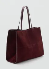 Bolso tipo shopper de piel de serraje en color bordó, con diseño estructurado, doble asa de hombro y cierre de botón magnético. Incluye forro interior de algodón y bolsillo con cierre de cremallera.