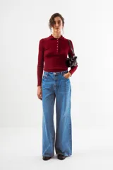 Top de tejido de punto acanalado color bordó, de manga larga y cuello polo con botones frontales.