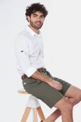 Bermuda clásica color verde militar con bolsillos laterales, trabillas para cinturón y cierre frontal con botón y cremallera.