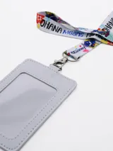 Tarjetero de material sintético con diseño estampado de Stitch y la frase 'Ohana Means Family', incluye cinta para el cuello a juego con el mismo diseño y gancho metálico.