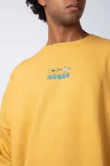 Buzo de cuello redondo y corte oversize, confeccionado en tela rústica color amarillo. Presenta un pequeño estampado central en el pecho con un avión y olas.