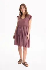 Vestido corto de viscosa color beige, sin mangas con volados en las sisas, escote en V y diseño escalonado.