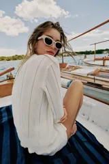 Chaqueta de punto blanco con diseño pointelle, cuello redondo, manga larga y cierre frontal con botones.