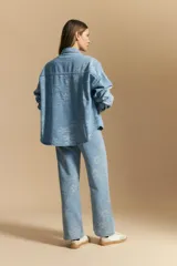 Sobrecamisa de denim celeste con estampado floral tono sobre tono. Presenta cuello camisero, cartera frontal con botones metálicos y bolsillos aplicados en el pecho.