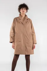 Gabardina color beige de largo medio con corte regular, fabricada en nailon repelente al agua. Tiene costuras interiores con ribete de nailon, cierre frontal con botones ocultos, escote medio bajo con cuello solapa, puño ancho con ventilación, manga de una pieza con costura en el puño, bolsillo de ribete inclinado y parche de logotipo de silicona.
