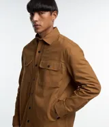 Camisa de manga larga confeccionada en sarga de algodón color verde menta, con cuello inglés y cierre frontal de botones negros. Presenta dos bolsillos de parche con solapa en el pecho y puños con botones.
