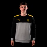 Buzo de cuello redondo Puma del Club Atlético Peñarol. Presenta un diseño de bloques de color con la parte superior y mangas en negro, franjas amarillas en los hombros y la parte central en gris. Incluye el logo de Puma y el escudo del club en el pecho.