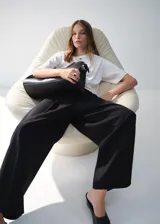Pantalón wide leg de tiro medio color negro, con diseño largo, bolsillos laterales, bolsillos de ribete posteriores y detalle de pinzas. Cuenta con cierre oculto de botón, gancho y cremallera, e incluye forro interior.