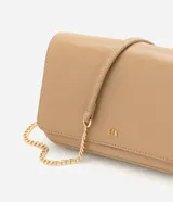Cartera bandolera Satinato pequeña de color marrón oscuro, confeccionada en poliuretano con detalles de herrajes dorados y correa larga de cadena. Cuenta con solapa frontal y múltiples compartimentos internos.