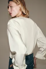 Camisa blanca ZARA Woman Collection de 100% seda, con escote en V ajustable con cordones entrelazados y manga larga con puños rectos.