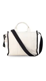 Bolso tipo tote bag de lona color beige con detalles de ribetes negros. Presenta el texto 'THE TOTE BAG' y 'LINCOLN'S' estampado en el frente. Cuenta con doble asa superior y correa ajustable extraíble.