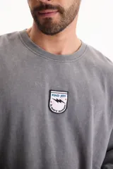 Buzo gris con efecto lavado, cuello redondo, mangas largas y un pequeño parche bordado en el pecho con la leyenda "Find Joy".