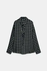 Camisa de mujer con estampado de cuadros vichy en tonos verde oscuro y negro, confeccionada en mezcla de viscosa. Presenta cuello solapa, manga larga con puños, cierre frontal con botones y un detalle de pañuelo integrado en el mismo tejido.