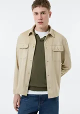 Campera ligera de gamuza en color beige, con diseño de estilo sobrecamisa, cierre frontal de botones, cuello clásico y dos bolsillos frontales con solapa y botón.