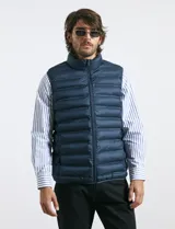 Chaleco acolchado de diseño capitoneado con cierre frontal al tono, cuello alto y ribetes en sisas y ruedo.