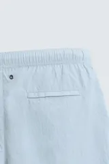 Bañador de hombre de largo medio, color celeste claro con rayas blancas horizontales. Presenta cintura elástica ajustable con cordón, bolsillos frontales y bolsillos traseros de plastrón. Incluye forro interior.