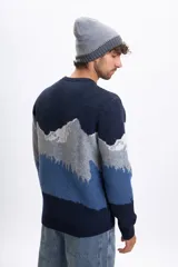 Buzo de punto con cuello redondo y diseño estampado de paisaje montañoso en tonos azules, grises y blancos. Presenta puños y ruedo acanalados.