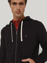 Buzo de felpa de algodón azul marino con capucha con cordón, cierre de cremallera, dos bolsillos delanteros tipo canguro y logo de Tommy Hilfiger bordado en el pecho.