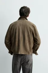 Cazadora de hombre confeccionada en piel con acabado de ante. Presenta un diseño de corte regular con cuello solapa, cierre frontal de botones, manga larga con puños abotonados y cuatro bolsillos frontales de plastrón.