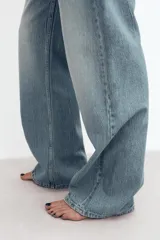 Jeans de denim de tiro medio y corte relaxed con diseño de cinco bolsillos, trabillas en la cintura y cierre frontal con cremallera y botón metálico.