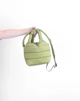 Bolsito tipo tote acolchado de color amarillo, con diseño de líneas horizontales y logo de la marca estampado en el frente. Cuenta con dos asas superiores acolchadas y una correa ajustable de cinta en color beige.