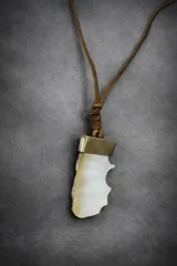 Collar con dije de nácar natural y detalle metálico dorado, suspendido de un tiento de cuero marrón.