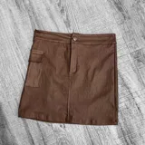 Minifalda marrón de cuero sintético con diseño cargo, cierre frontal con botón y bolsillos laterales.
