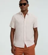 Camisa de corte regular confeccionada en mezcla de lino y algodón, con cuello inglés, manga corta y cierre frontal abotonado. Diseño liso en color beige de la marca Marfinno.