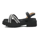 Sandalias de plataforma negra con suela dentada, tiras cruzadas en el empeine cubiertas de strass plateado y pulsera al tobillo con hebilla metálica.