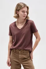 Remera marrón de manga corta con escote en V y diseño al cuerpo. Presenta un delicado detalle de tachas metálicas en forma de estampa en el hombro izquierdo.