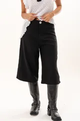 Bermuda de corte amplio y tiro alto en color negro, con cierre frontal de botón y bolsillos laterales.