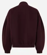 Campera estilo bomber de sarga color bordó, con cuello alto, cierre frontal con botones forrados, mangas largas con puños elásticos y bajo ajustado.