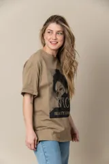 Remera blanca de algodón con estampa frontal de una mujer con anteojos y la inscripción "NYC Beauty Leopaid" con apliques de tachas.
