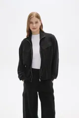 Campera negra de manga larga con cierre frontal, bolsillos frontales con solapa y cordón ajustable en la cintura.