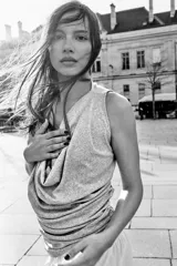 Top gris de escote drapeado, con una manga sisa y una manga corta. Presenta frunces laterales y un bajo asimétrico.