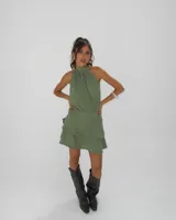 Vestido corto color verde militar con cuello halter alto, sin mangas y falda con volados superpuestos.
