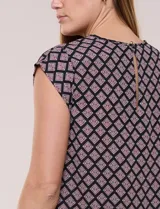 Blusa de gasa ligera con diseño geométrico en tonos oscuros, escote redondo, mangas cortas y bolsillo frontal aplicado. Presenta un ruedo redondeado y silueta relajada.