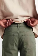 Pantalón de sarga color verde oliva, de corte ajustado, con cierre de botón y cremallera, bolsillos laterales y traseros.