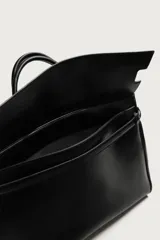 Bolso de mano extragrande negro de cuero sintético, con compartimento principal con cierre de imán, bolsillo interior con cierre y bolsillo secundario con solapa y detalle de cinta. Cuenta con dos asas de mano.