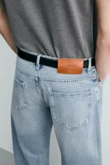 Jeans de denim de algodón en color negro con efecto lavado, corte amplio y silueta curva tipo barrel fit con pinzas en las rodillas. Presenta diseño clásico de cinco bolsillos y cierre frontal con cremallera y botón metálico.