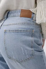 Jean celeste de calce recto y tiro medio-alto, con bordado de picas en tonos amarronados, lavado claro y ruedo desflecado.