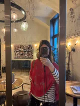 Poncho tejido en hilo de algodón, color rojo, con diseño de cuello redondo y terminaciones con flecos en el ruedo.